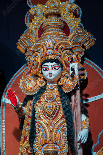 Goddess Saraswati idol , Durga Puja festival at night. Shot under colored light at Howrah, West Bengal, India. Biggest festival of Hinduism , celebrated all over the world.