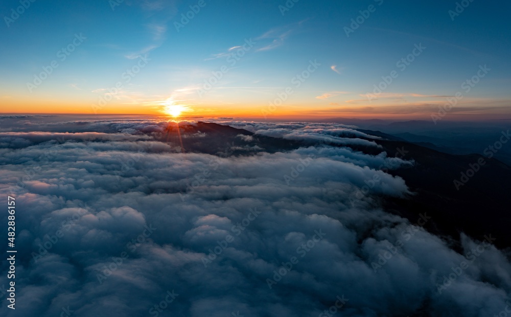 Sun shining brightly above white fluffy clouds at sunrise