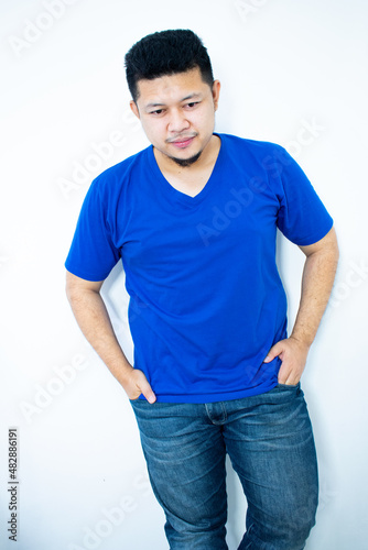 Young Asian man, standing, smiling, looking straight, wearing a blue shirt. in the white background © Igunt