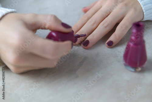 Hands of a young girl painting her nails by herself