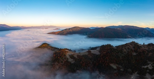 Thick fog among peaks of high autumn mountains at sunrise © YouraPechkin