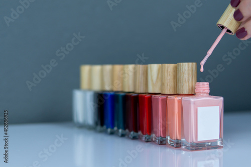 Set of nail polish colors in a row with a woman's hand holding a brush of an open nail polish