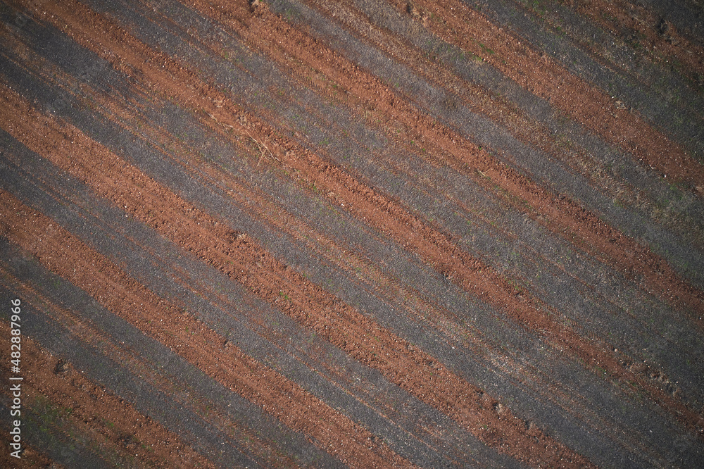 Striped texture brown red color aerial view. Texture of arable land top view. Winter texture plowed land drone view. Italian arable land in winter season top view.