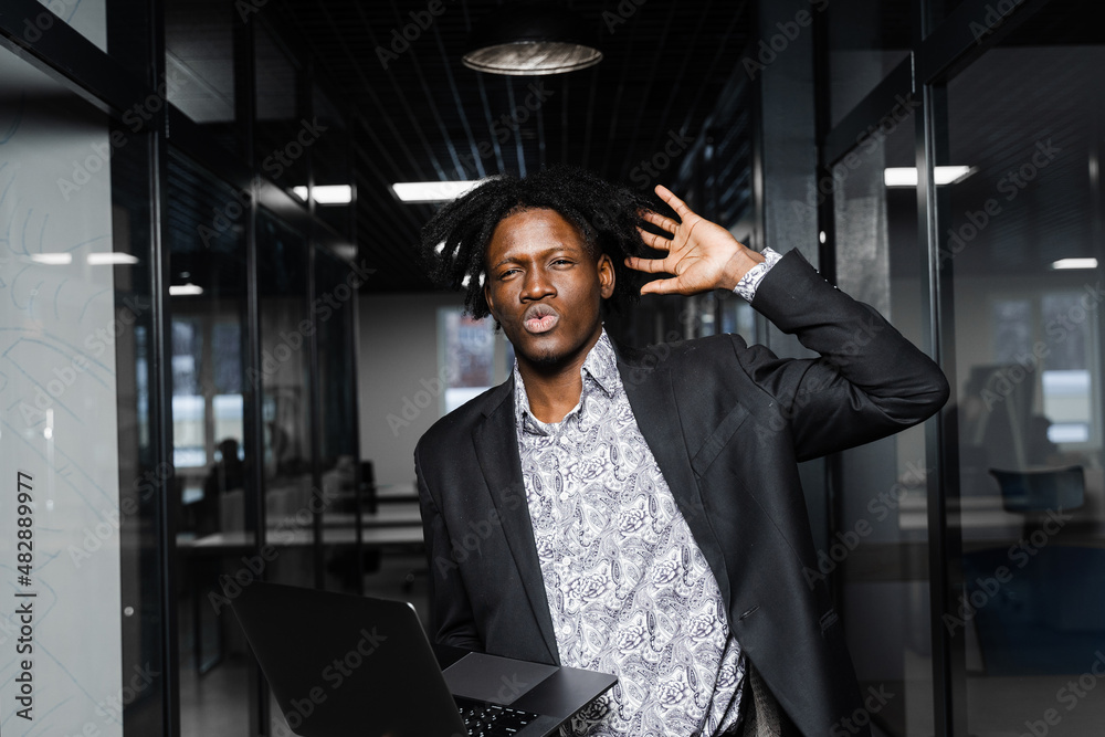 Surprised black man with laptop in the office. Shocked emotional handsome african business man in coworking space. Surprised black man with laptop in the office. Shocked emotional handsome african business man in coworking space.