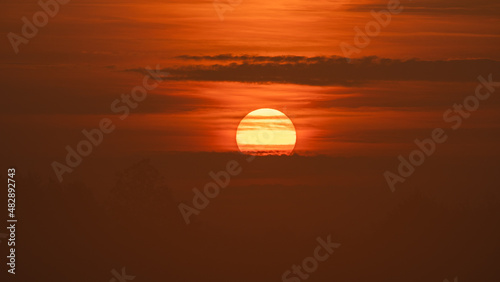 Beautiful wild sunrise and orange cloudy sky. The sun behind the clouds