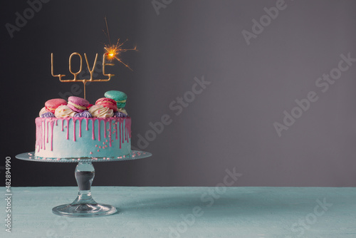cake with pink and blue decor and sparkler with text love