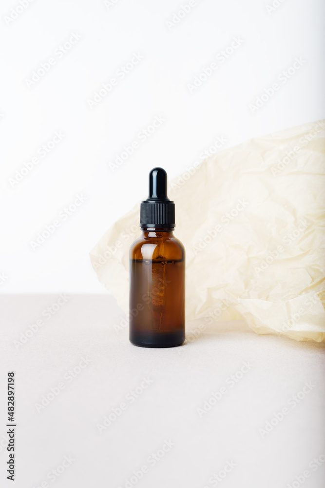 Serum glass bottle with pipette on the beige wrinkle paper background. Natural Organic Spa Cosmetic concept. Front view. Place for your text. Serum glass bottle with pipette on the beige wrinkle paper background. Natural Organic Spa Cosmetic concept. Front view. Place for your text.
