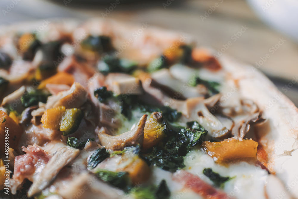 Homemade Veggie pizza with mushroom and pumpkins served on rounded wooden plate.