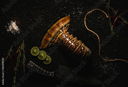   LANGOSTA  sobre laja de piedra  con decoración como sal, pimienta limón, chile de árbol  , romero y un cuchillo   photo