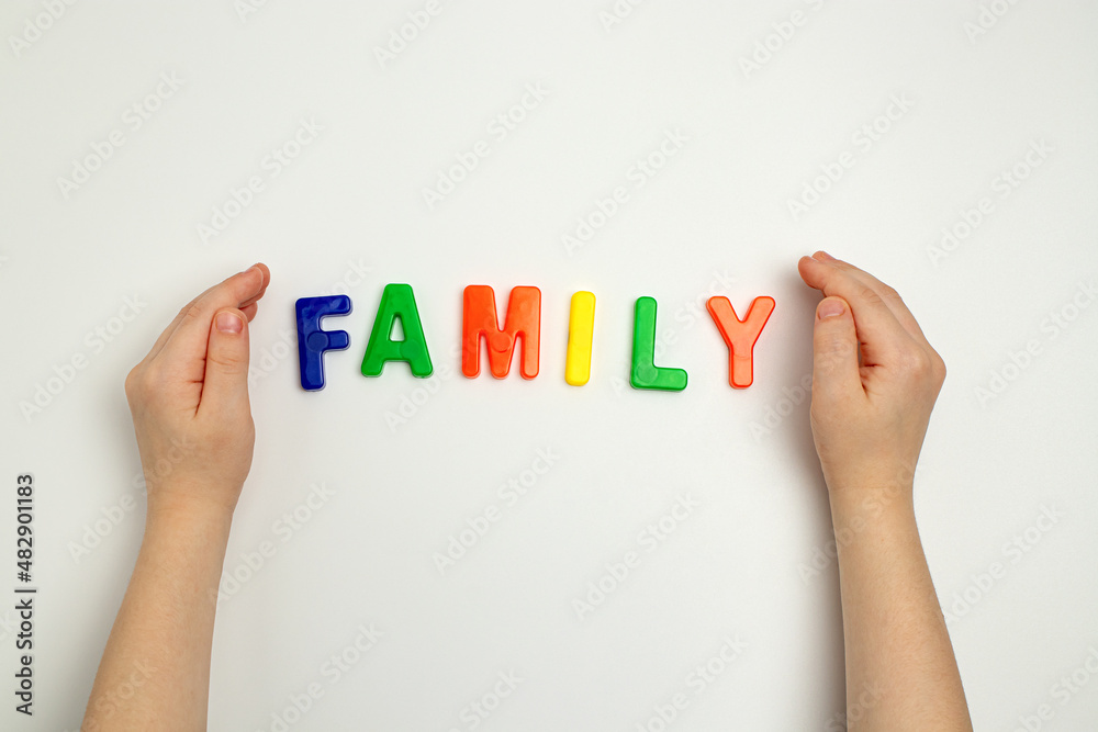 The child's hands and the word family made of multicolored letters The child's hands and the word family made of multicolored letters