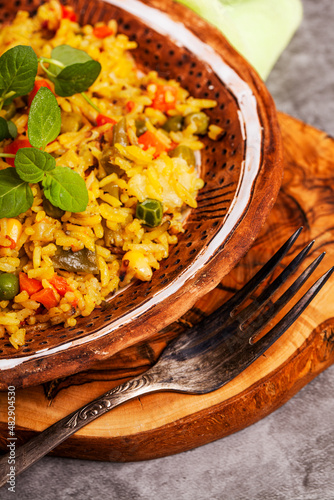 Healthy vegan food - vegetable pilaf from Indian cuisine, close up. Homemade delicious pilaf with beans, fresh parsley and ripe vegetables on a dark background close up. Top view
