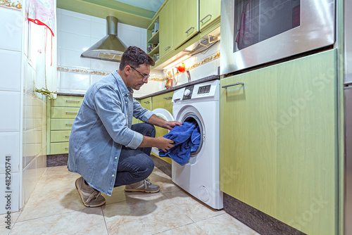 adult man with glasses putting the washing machine on