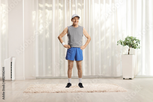 Full length portrait of an elderly man in sportswear standing on a carpet