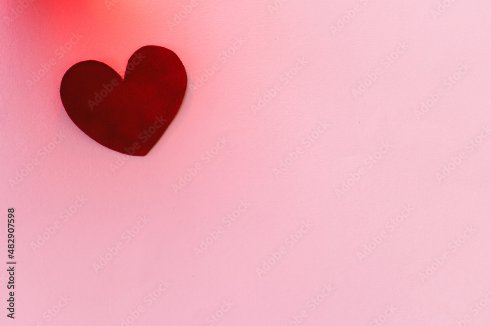 Happy Valentines Day banner. Love concept. Stylish valentine heart in red light on pink background, flat lay with space for text. Valentines day card template. Velvet heart on pink paper.