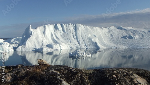 piękne kry i góry lodowe na spokojnym morzu odbijające się w tafli wody w słoneczny dzień