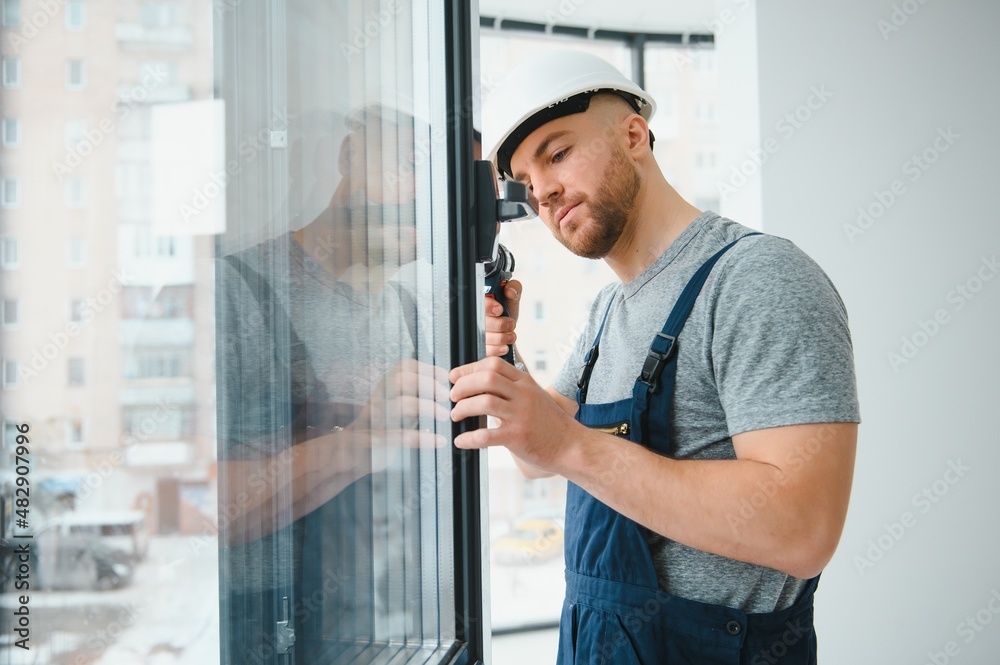 Fototapeta premium Construction worker repairing plastic window with screwdriver indoors, space for text. Banner design