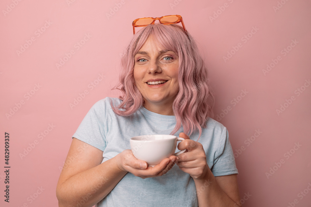 Attractive beautiful female woman hand holds hot cup coffee drink and teapot tea look at camera enjoying sunny morning isolated over pink wall background. Attractive beautiful female woman hand holds hot cup coffee drink and teapot tea look at camera enjoying sunny morning isolated over pink wall background.