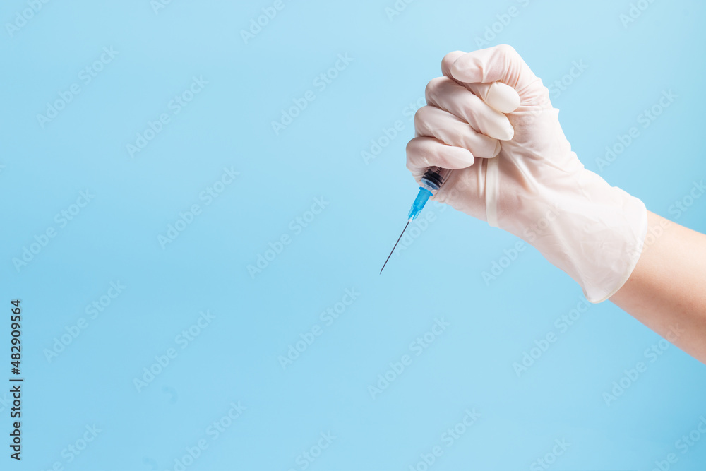 Forced vaccination. Hand with syringe on blue with copy space. Illigal vaccination. Forced vaccination. Hand with syringe on blue with copy space. Illigal vaccination.