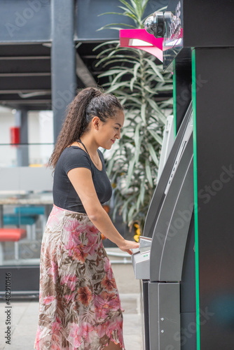 Young woman withdrawing money from an ATM.