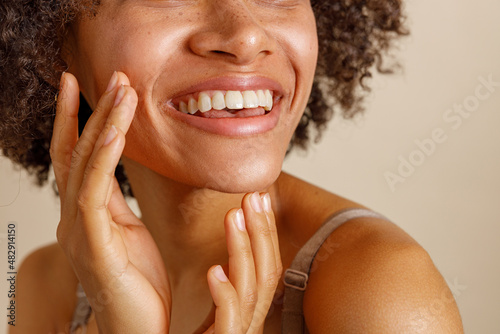 Slika na platnu Multiethnic woman toothy smiling on beige background of studio