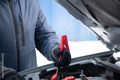 Jumper starter.We start the car in a severe frost on the street. photo