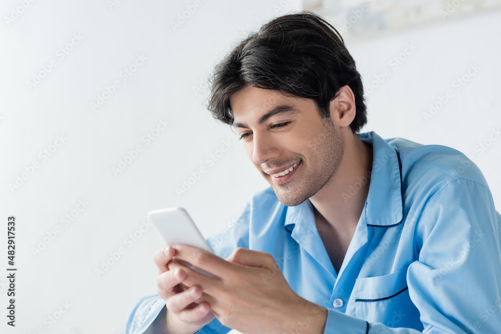 happy brunette man in blue pajamas chatting on mobile phone. happy brunette man in blue pajamas chatting on mobile phone.