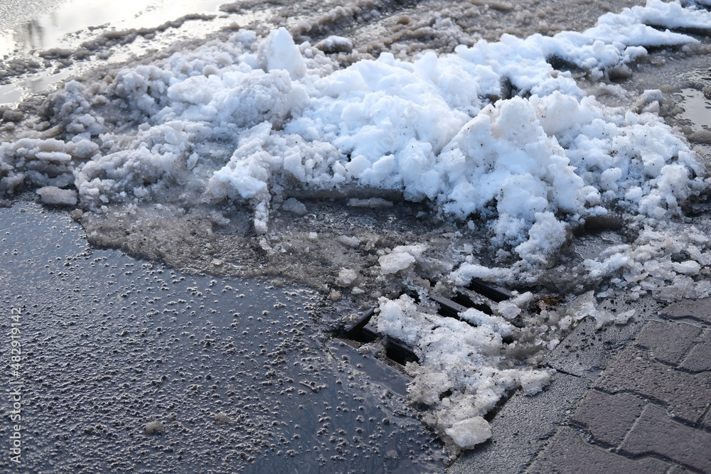 part of street in city, drainage runoff, pavement after heavy snowfall, wet snow melts, slush and mud impede movement of pedestrians and vehicles, concept traffic safety, work of public utilities