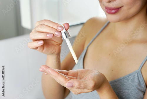 Beautiful woman holding a pipette in her hand with serum moisturizing anti aging antioxidant. Focus on hand. photo