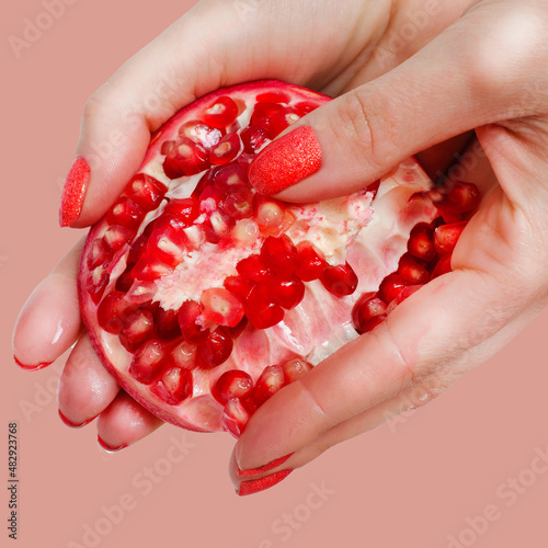 Hands holding grenade fruit on pinkish background