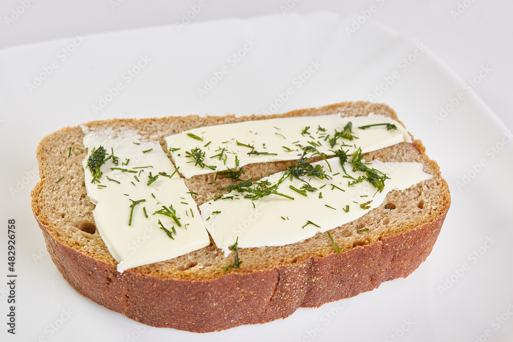 Sandwich of rye bread, butter and greens.