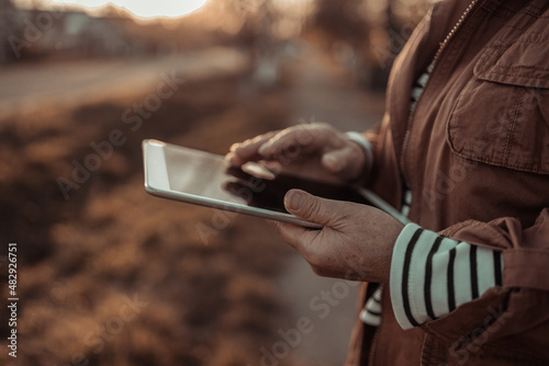 Closeup of female hands holding and using tablet pc, online shopping in the outdoors street background