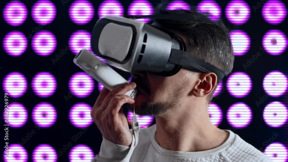 A man with virtual reality glasses makes a toast and drinks an alcoholic beverage with a joystick