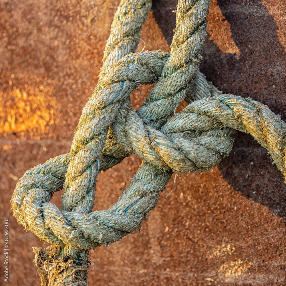 Knotted rope against rusty metal background