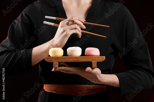 Photography Beautiful young woman with tasty Japanese mochi on black background