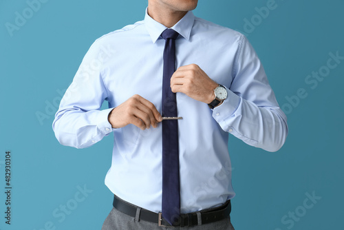 Bild auf Leinwand Handsome man in formal clothes adjusting tie on color background, closeup