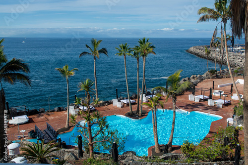 Fototapeta Naklejka Na Ścianę i Meble -  Beach club with blue swimming pool and palm trees on coast of Atlantic ocean, Costa Adeje, Tenerife, Spain