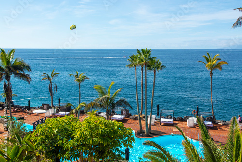 Beach club with blue swimming pool and palm trees on coast of Atlantic ocean, Costa Adeje, Tenerife, Spain photo