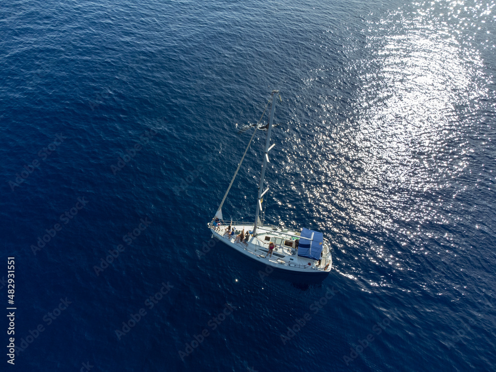 Aerial top view on dark blue water of Atlantic ocean and white sailboat with tourists