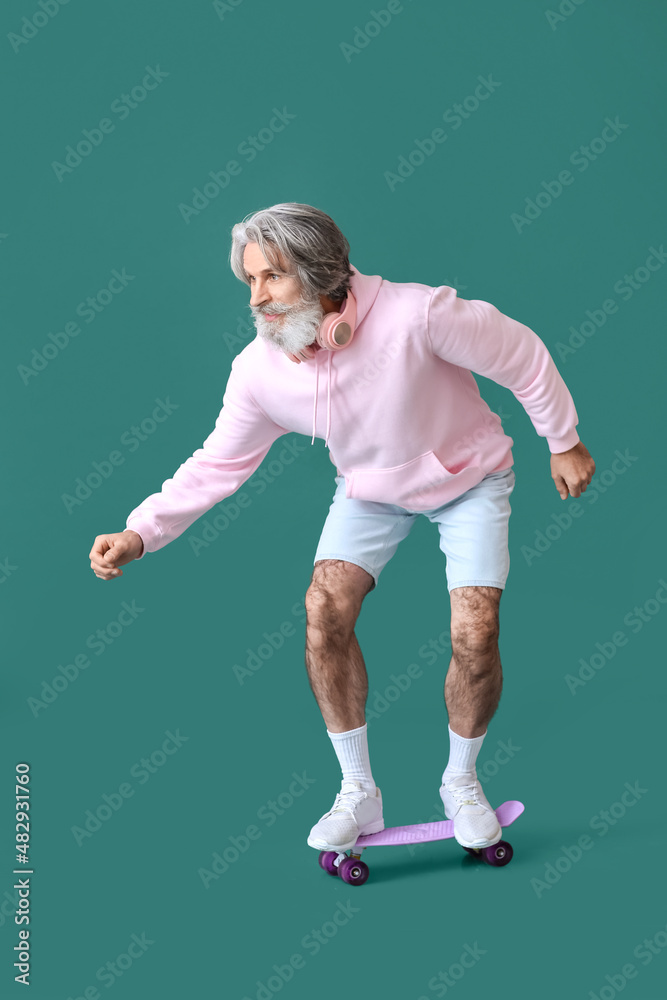 Senior man with skateboard on green background Senior man with skateboard on green background