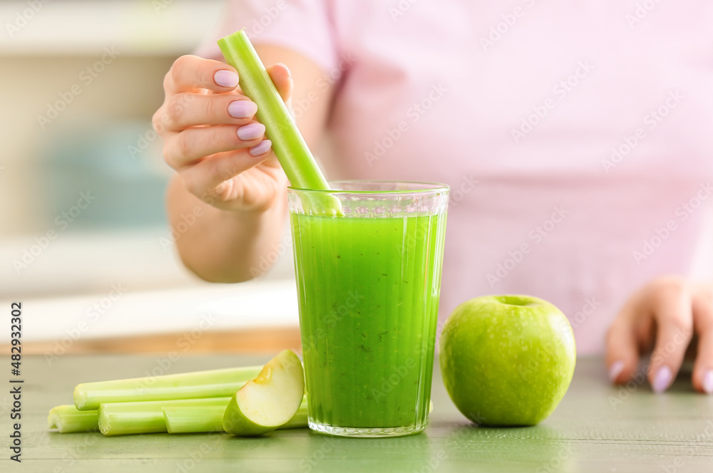 Woman preparing healthy green juice at kitchen table, closeup Woman preparing healthy green juice at kitchen table, closeup