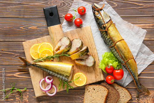 Board with smoked mackerel fishes on wooden background