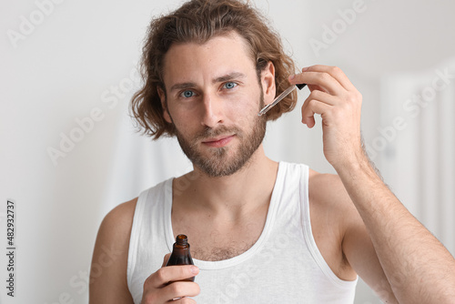 Young man using serum for s...