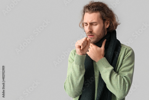Ill man with sore throat on grey background photo