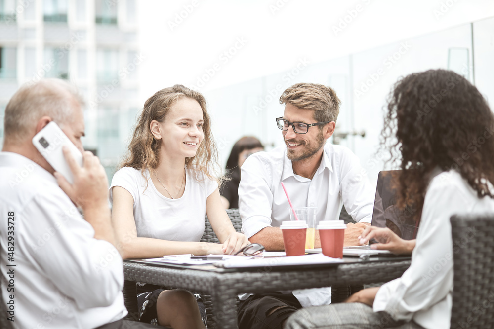 Smiling colleagues working together developing business strategy for their next project. Young casually dressed business people having discussion on sunny terrace. Modern job in comfortable conditions Smiling colleagues working together developing business strategy for their next project. Young casually dressed business people having discussion on sunny terrace. Modern job in comfortable conditions