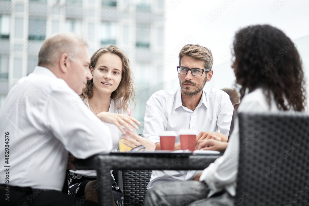 Smiling colleagues working together developing business strategy for their next project. Young casually dressed business people having discussion on sunny terrace. Modern job in comfortable conditions Smiling colleagues working together developing business strategy for their next project. Young casually dressed business people having discussion on sunny terrace. Modern job in comfortable conditions