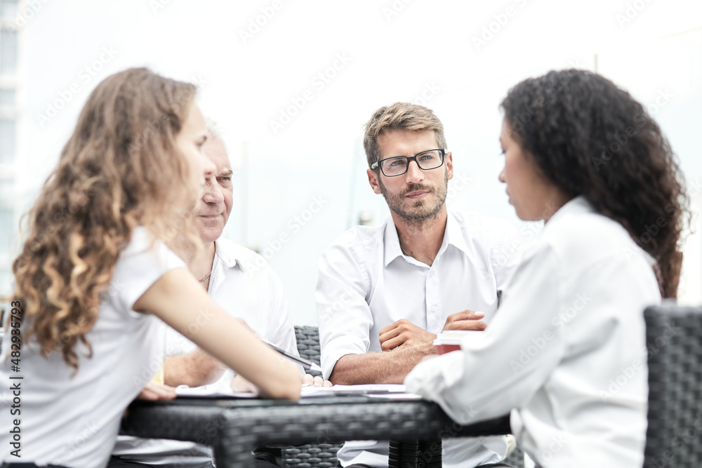 Smiling colleagues working together developing business strategy for their next project. Young casually dressed business people having discussion on sunny terrace. Modern job in comfortable conditions