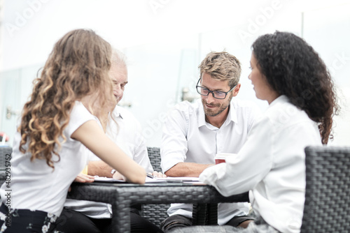 Smiling colleagues working together developing business strategy for their next project. Young casually dressed business people having discussion on sunny terrace. Modern job in comfortable conditions