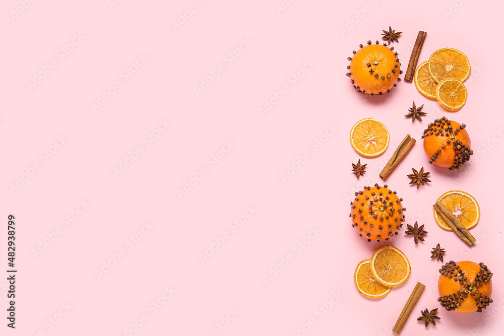 Handmade Christmas decoration made of tangerines with cloves on pink background