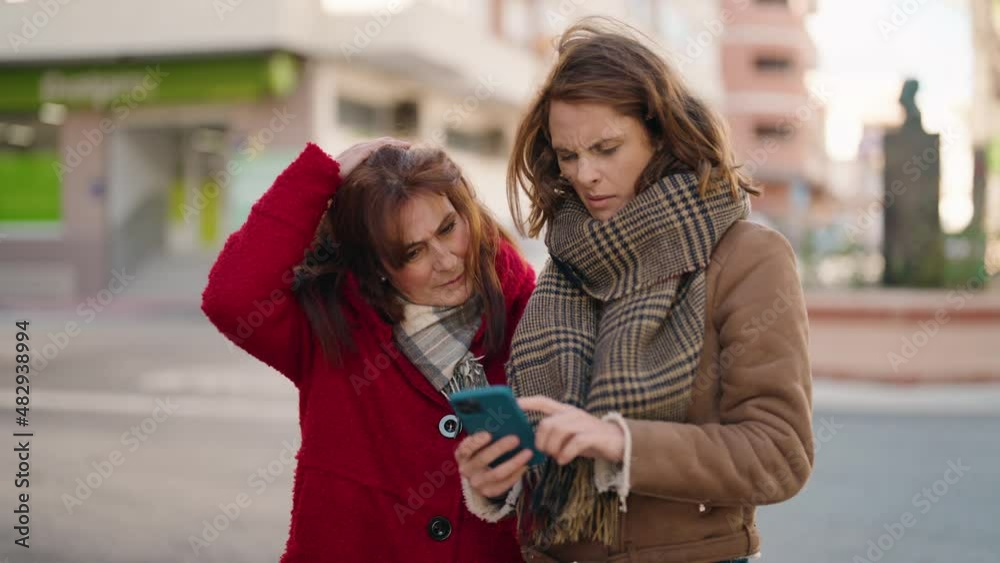 Mother and daughter with winner expression using smartphone at street Mother and daughter with winner expression using smartphone at street