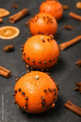 Handmade Christmas decoration made of tangerines with cloves on dark background, closeup